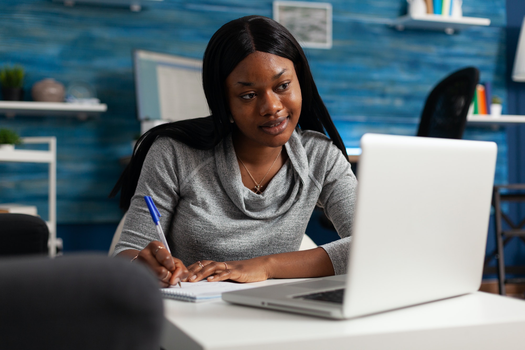 Woman taking notes at her laptop while planning business systems to overcome a growth plateau