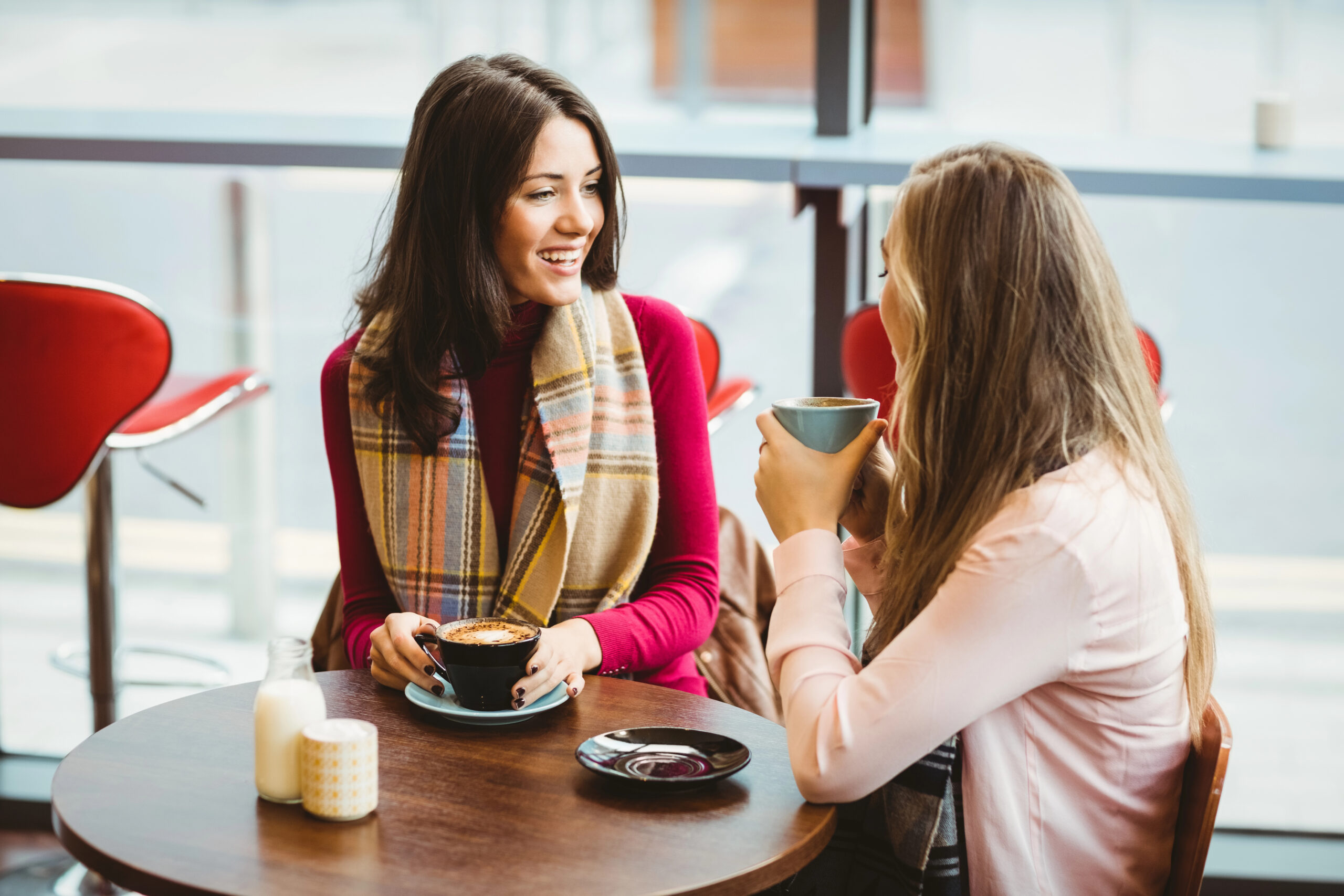 Two women talking over coffee in a client meeting, getting to know the client's business