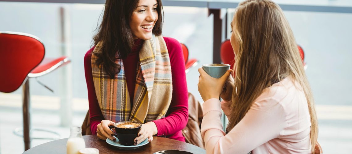 Two women talking over coffee in a client meeting, getting to know the client's business